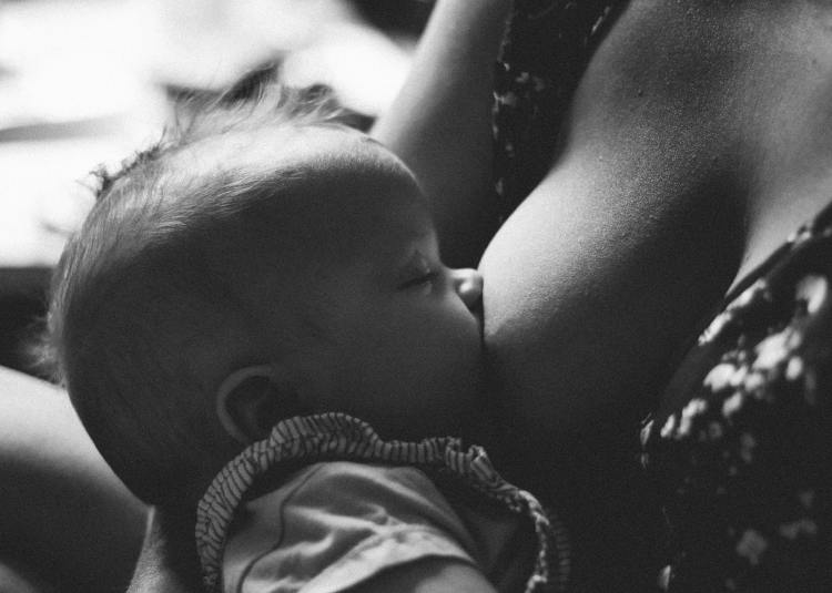 Decorative. A baby breastfeeds. The baby's eyes are closed. 
